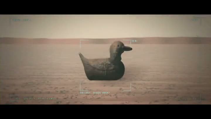 Video poster showing a duck model on desert-like ground, seen through a rover camera's targeting view
